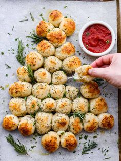 a person dipping sauce on top of some scallops with rosemary sprigs