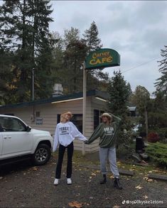 two people holding hands in front of a car and coffee shop with a green sign