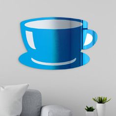 a blue coffee cup shaped mirror mounted on the wall above a couch in a living room