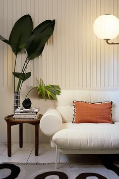 a white couch sitting next to a table with a potted plant on top of it