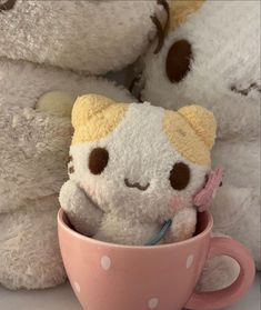 two white teddy bears sitting next to each other with a pink coffee cup in front of them