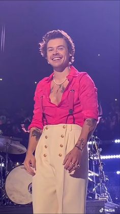 a man in pink shirt and white pants on stage