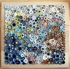 a painting made out of many different types of buttons on a wooden board with wood trim around the edges