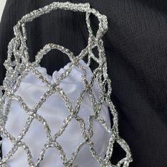 a white purse with silver chains hanging from it's side, on top of a black shirt