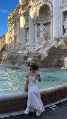 a woman sitting on the edge of a fountain