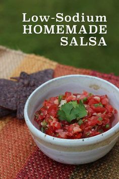 a white bowl filled with salsa sitting on top of a table next to tortilla chips