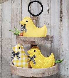 three yellow chickens sitting on top of a wooden shelf