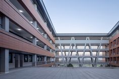 an empty courtyard in front of a building with many windows and lights on the ceiling