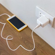 an electronic device plugged into the wall with a charger attached to it on a wooden floor