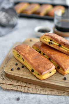 three pastries on a cutting board with coffee and other food items in the background