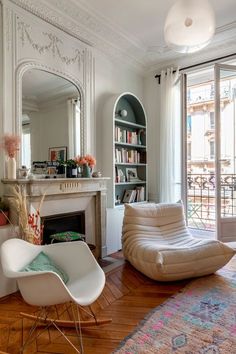 a living room filled with furniture and a fire place in front of a mirror on the wall