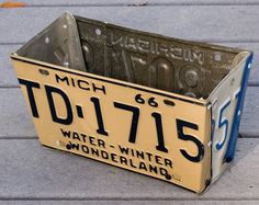 an old license plate from michigan sits on the sidewalk in front of a building that is being used as a planter