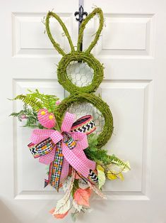 a wreath is hanging on the front door with an easter bunny's head made out of moss