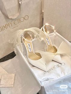 white jimmy choo shoes are on display in front of the store's packaging