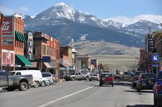 cars are driving down the street in front of mountains