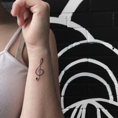 a woman's arm with a musical note tattoo on it