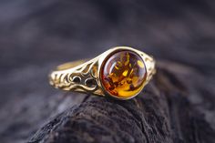 Art Gemelli present's lovely ring made of natural Baltic amber. It has been lovely set in sterling silver and covered by 14 CT gold layer. Cognac type of amber. Celtic heritage inspired design. Perfect for everyday use. Ideal gift.    Perfectly polished cognac Baltic amber set in 925 sterling silver setting and covered by 14 CT gold layer.    This ring comes with LIFETIME CRAFTWORK WARRANTY for your peace of mind. Gift wrap is also provided.    We source our amber from Baltic coast often looking Baltic Amber Ring, Amber And Gold Jewelry, Celtic Heritage, Celtic Design, Medieval Jewelry, International Jewelry, Amber Ring, Handcrafted Art, Classy Jewelry