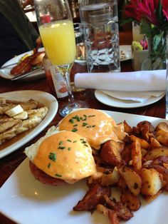 a breakfast plate with eggs benedict, potatoes and french fries on the side at a restaurant