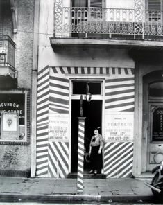 an old black and white photo of a woman entering a store