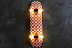 an orange and white checkered skateboard with some lights on it's side