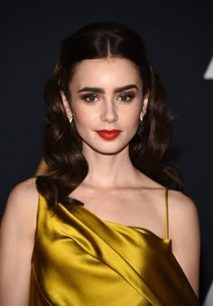 an image of a woman with long hair wearing a gold dress and red lipstick at the oscars