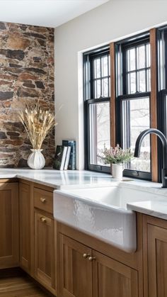 a kitchen with wooden cabinets and white counter tops, along with a stone wall behind the sink