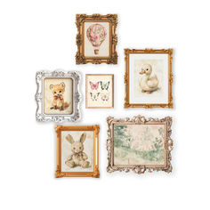 four framed pictures hang on the wall in different styles and sizes, including one with a teddy bear