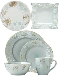 an assortment of white and gold dinnerware with sea shells on the rims,