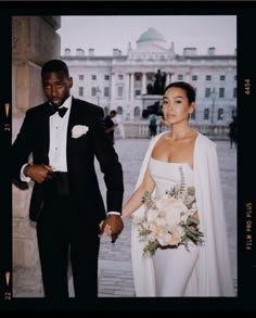 a bride and groom holding hands in front of a building