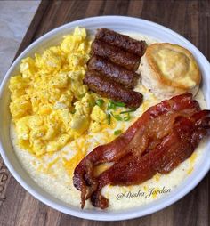 a white plate topped with eggs, bacon and english muffins on top of a wooden table