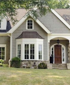 a gray house with white trim and two story windows on the front door is shown