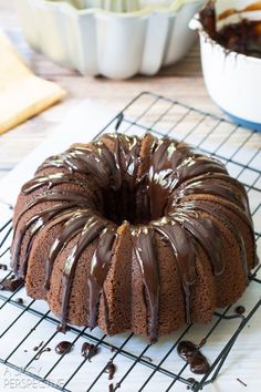 a bundt cake with chocolate icing and caramel drizzle on a cooling rack