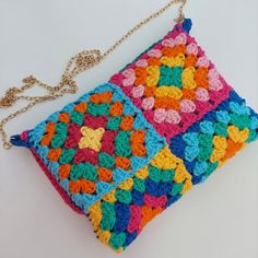 a multicolored crocheted purse on a white surface with a gold chain