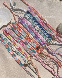 several bracelets are laid out on the ground next to a shell and seashell