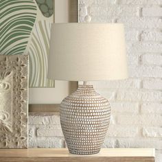 a lamp sitting on top of a wooden table next to a painting and framed pictures