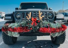 a jeep decorated for christmas with reindeer antlers and wreaths on the front bumper