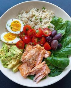 a white bowl filled with meat, vegetables and rice next to an egg on top of lettuce