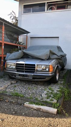 a car covered with a tarp parked in front of a garage next to a building