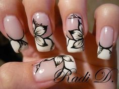 a woman's hand with white and black flowers painted on the nail polishes