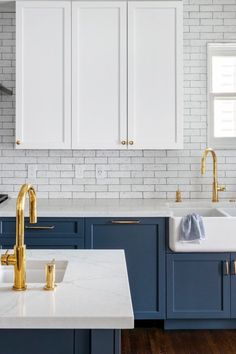 a kitchen with blue cabinets and gold faucets on the countertops, along with white brick walls