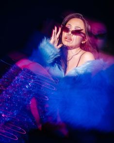 a woman in blue and purple is holding her hand up to her face while wearing sunglasses