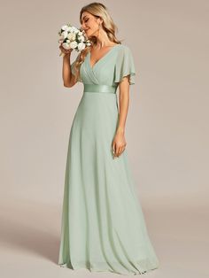 a woman in a long green dress holding flowers