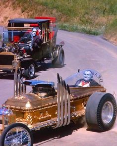 an old timey car driving down the road with other antique cars behind it on display