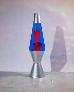 a blue and red vase sitting on top of a metal table next to a white wall