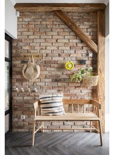 a wooden bench in front of a brick wall with baskets on it and a basket hanging from the ceiling