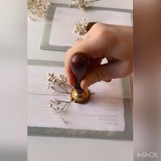 a person is stamping some flowers with a small metal object in front of them