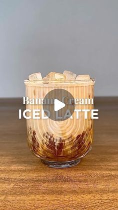 an ice latte in a glass on top of a wooden table with the words banana cream iced latte