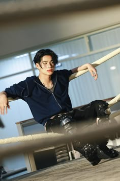 a man sitting on top of a wooden floor next to a rope