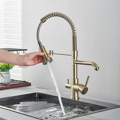 a person is washing their hands under a kitchen faucet with water running from it