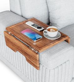 a coffee table with a cell phone, remote control and cup of coffee on it